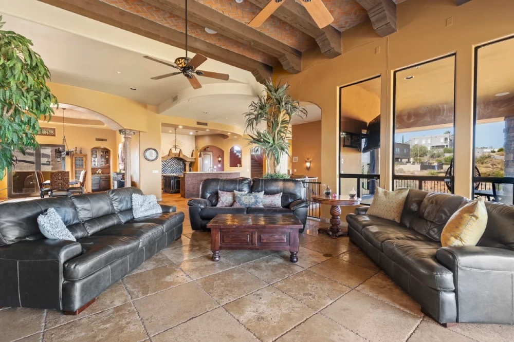 Open great room with leather sofas, wood-beam ceiling and wide desert-view windows
